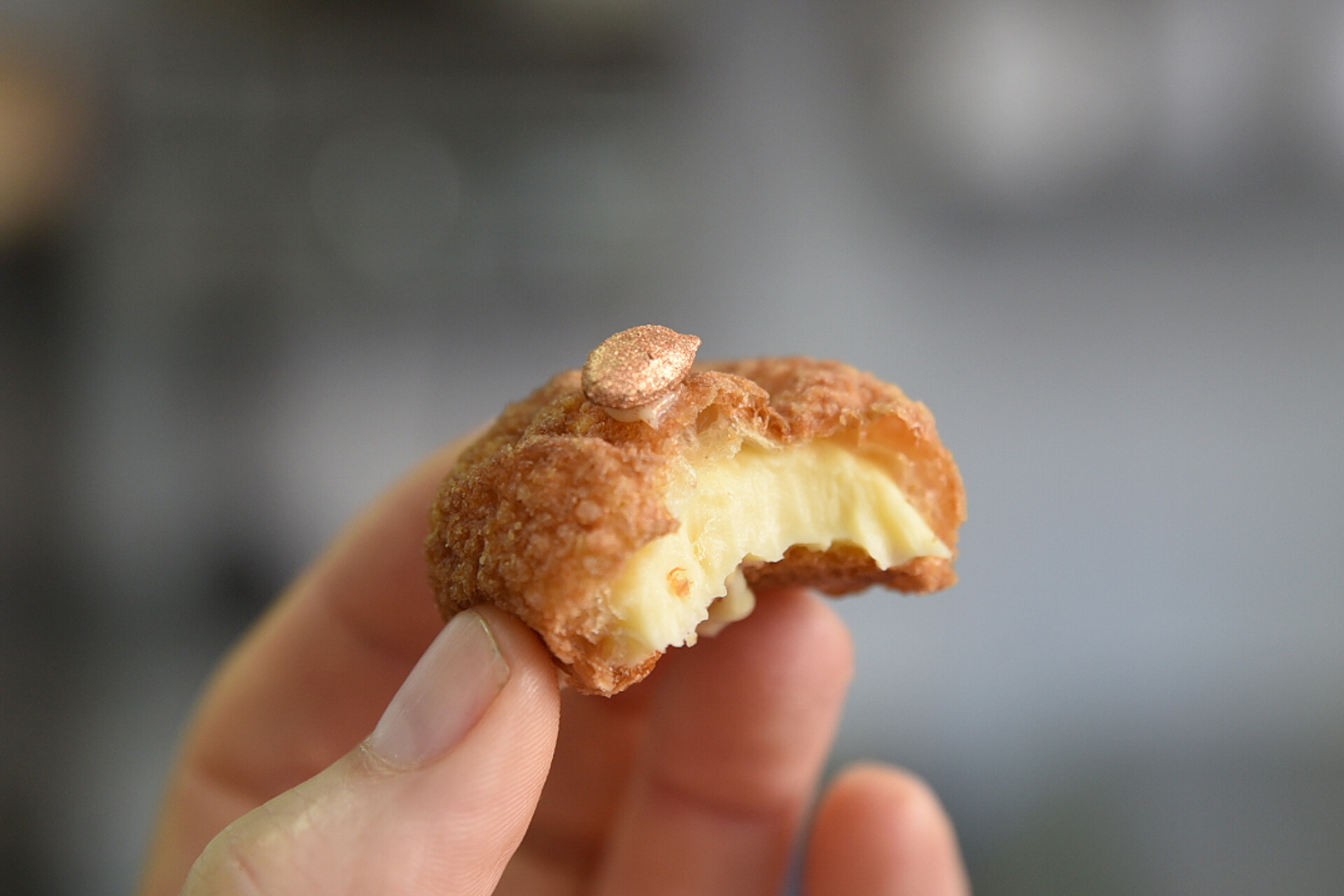 Une main qui tient un petit chou au fromage avec une graine de courgé dorée