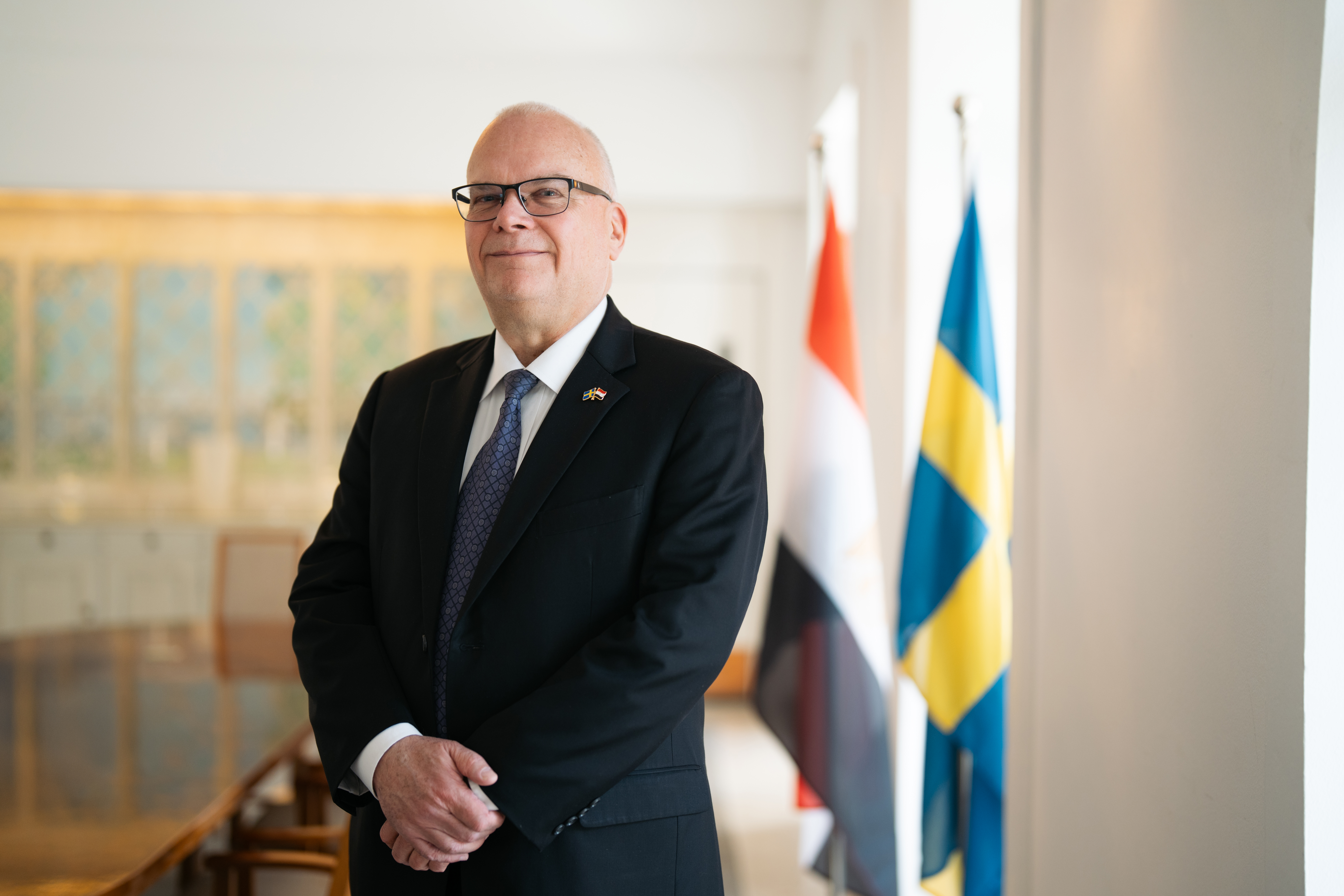 Photo of Ambassador Dag Juhlin-Dannfelt at the Swedish Residence in Cairo, Egypt, with the Swedish and Egyptian Flags side to side in the background.