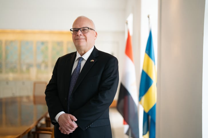 Photo of Ambassador Dag Juhlin-Dannfelt at the Swedish Residence in Cairo, Egypt, with the Swedish and Egyptian Flags side to side in the background.