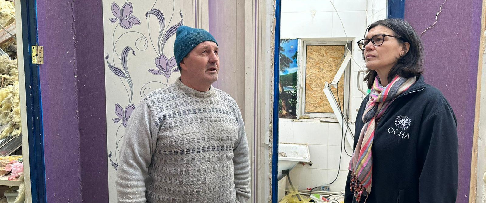 Sarah Hilding der Weduwen från OCHA tillsammans med en ukrainsk man i ett bombskadat hus.