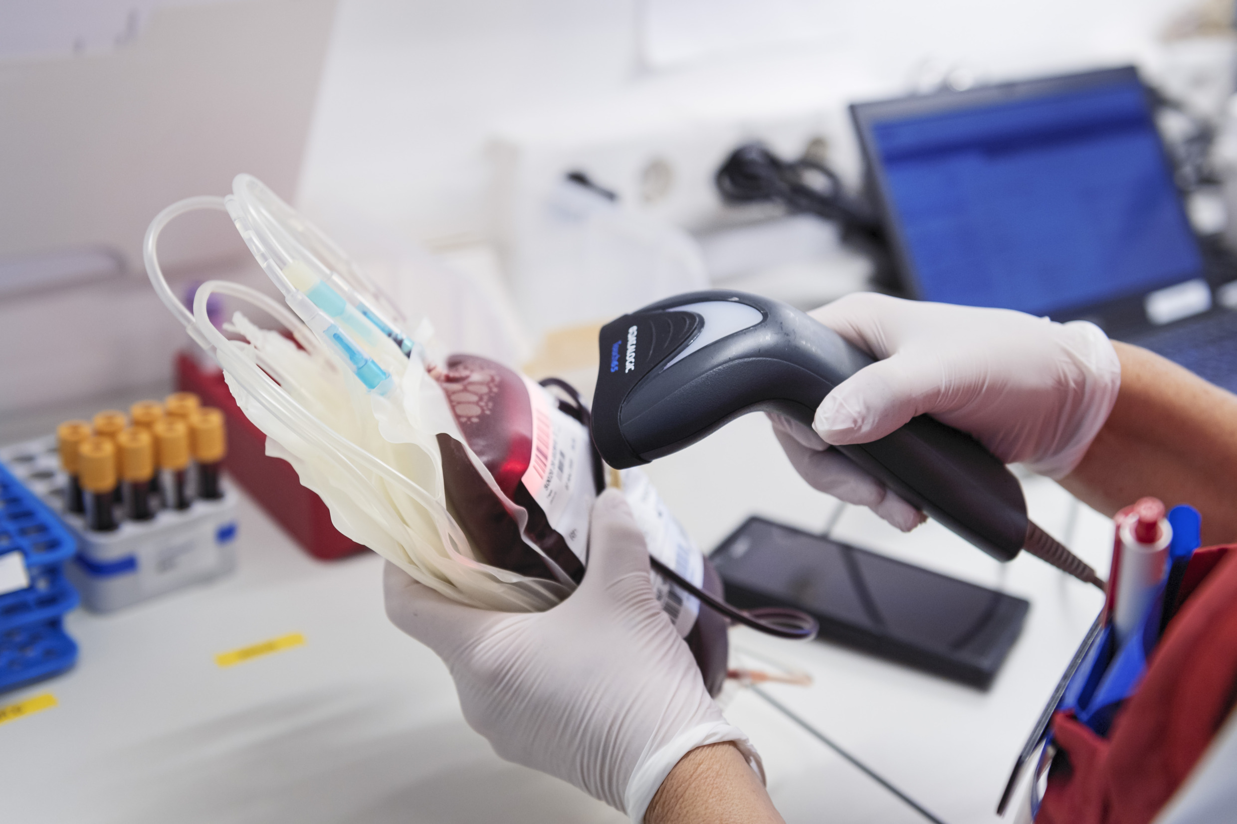 Une main de médécin qui scan un sachet contenant du sang.