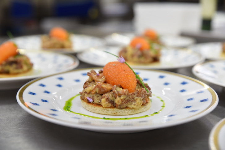 Tartine avec des girolles et des œufs d’ablette de Kalix sur une assiette blanche avec des couronnes bleues.
