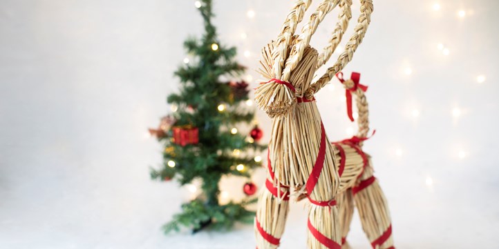 Foto på julbock framför en gran