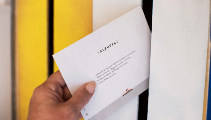 Ett valkuvert med texten stoppas in i en låda.